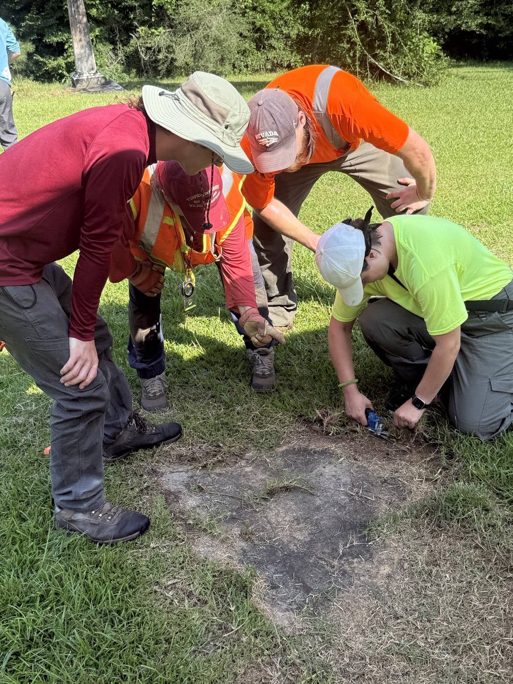 Participants examining and caring for a grave marker during cemetery preservation training